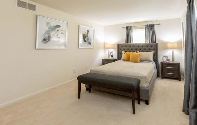 A bedroom with a large bed and two framed pictures on the wall.