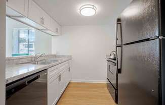 an empty kitchen with stainless steel appliances and white cabinets