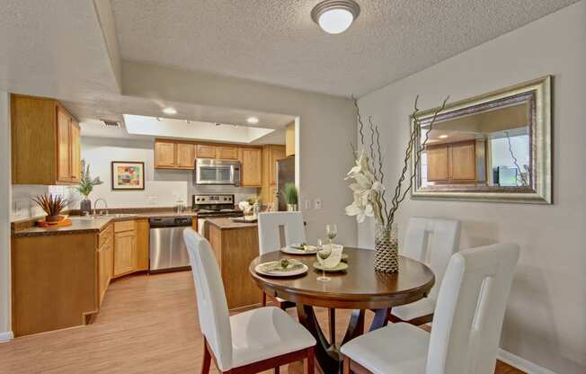 a dining area with a table and chairs and a kitchen in the background