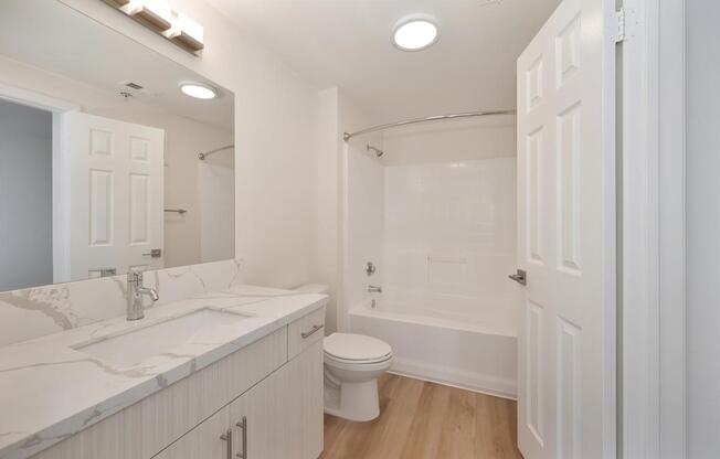 A white bathroom with a toilet, sink, and bathtub.