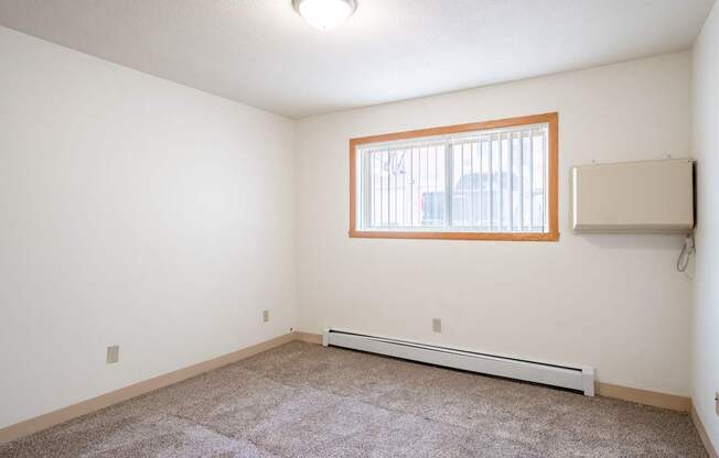 A room with a window and a carpet on the floor. Fargo, ND Islander Apartments