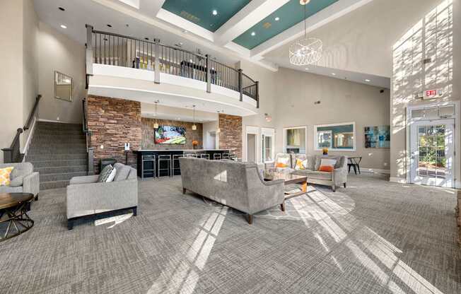 the lobby of a clubhouse with couches and chairs and a fireplace