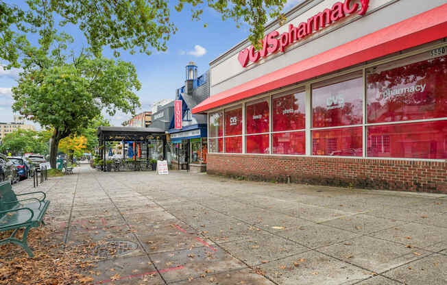 A red and white pharmacy with a green bench in front.