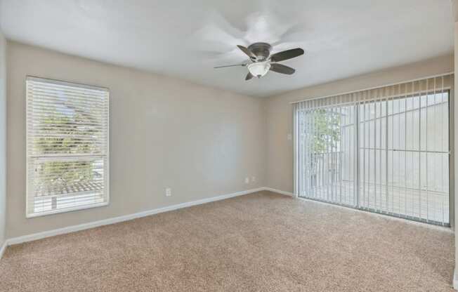 an empty living room with a ceiling fan and a window