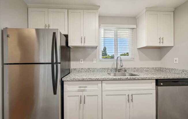 a kitchen with white cabinets and a stainless steel refrigerator