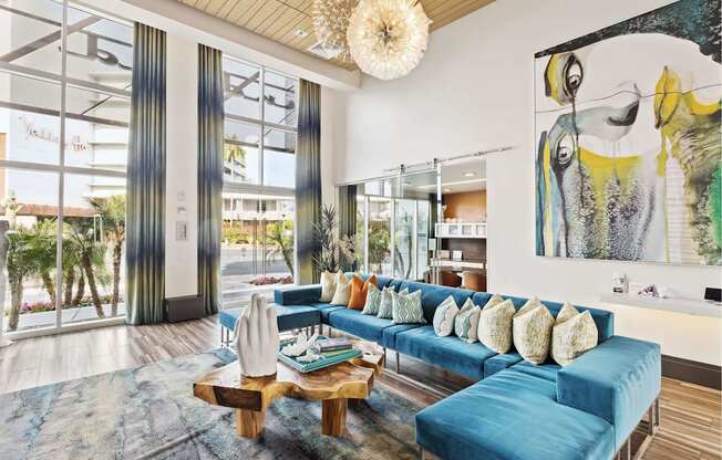 A living room with a blue couch and a large painting on the wall.