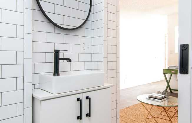 a small bathroom with white subway tile and a white sink with a black faucet