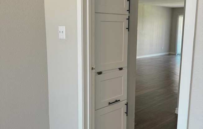 an open white door leading into a hallway with a wood floor