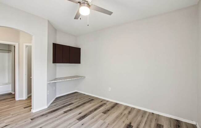 A room with a ceiling fan and wooden flooring.