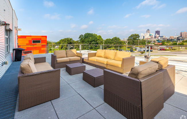 a rooftop patio with furniture and a city in the background
