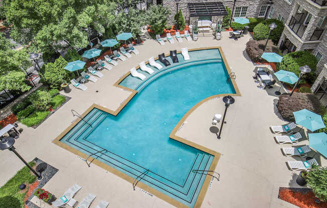 A large outdoor swimming pool surrounded by lounge chairs and umbrellas.