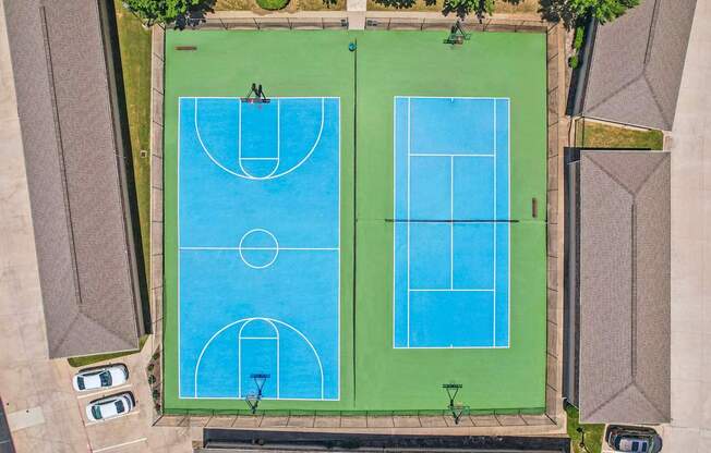 Two blue tennis courts surrounded by green grass.