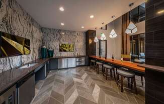 A modern bar with a marble patterned wall and wooden stools.