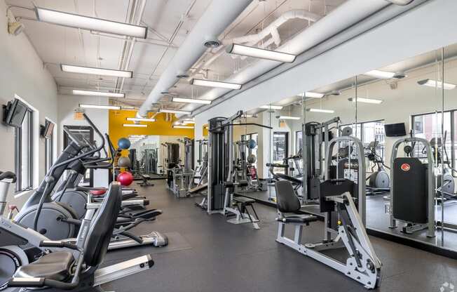 a gym with cardio equipment and weights on the floor