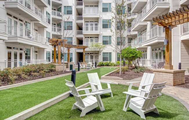 chairs and a firepit on the grassy courtyard of an apartment complex