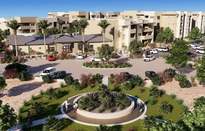 A landscaped community courtyard here at Reflect at Dobson Ranch showcasing a circular walking path surrounded by manicured greenery, desert plants, and palm trees, with a modern clubhouse, parked vehicles, and multi-story apartment buildings in the background under a clear blue sky.