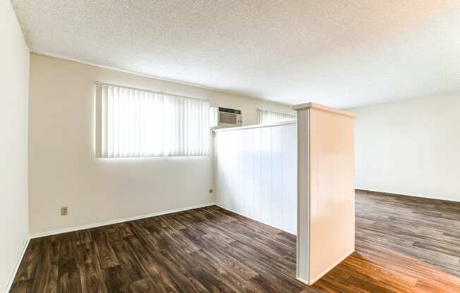 the spacious living room and dining room of an apartment with wood flooring