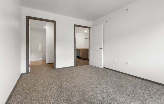 A room with a carpeted floor and two open doors.