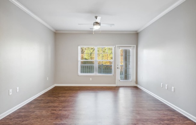 an empty living room with hardwood flooring and a window