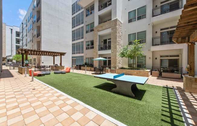 a courtyard with a ping pong table and a lawn