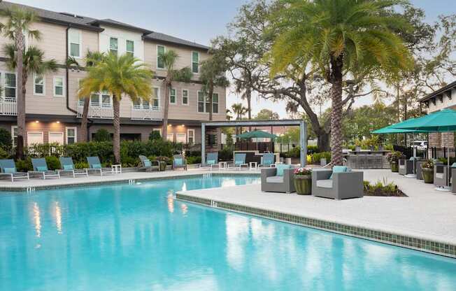 A swimming pool in front of a building with palm trees.