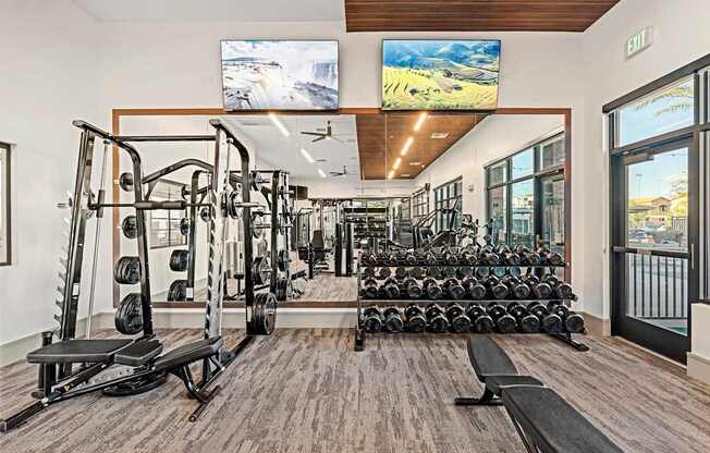 A gym with a variety of equipment including weights and treadmills.