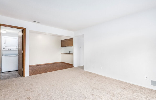 an empty living room with an open door to a laundry room