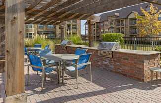 a patio with a barbecue grill and a table with chairs