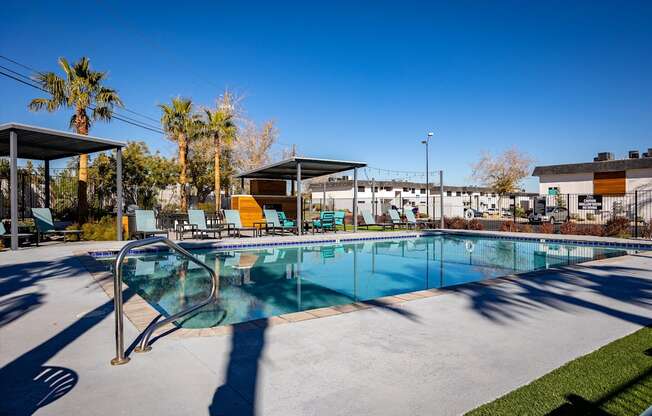 a swimming pool with lounge chairs and palm trees in the background