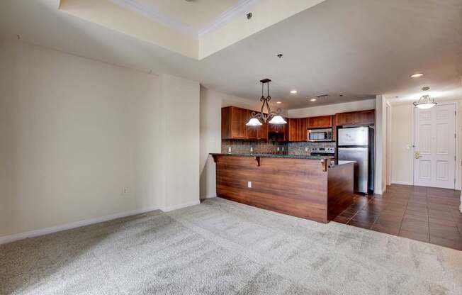 A spacious living room with a kitchen area in the background.