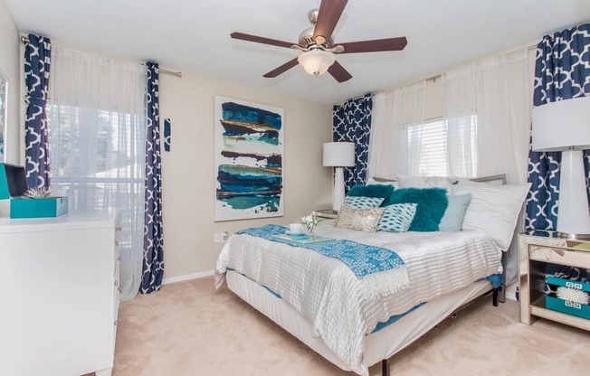 One, Two, and Three-Bedroom Apartments in Stockbridge, GA - Avenue 33 - Spacious Bedroom with Carpet Flooring, a Ceiling Fan, and Windows with Blinds.