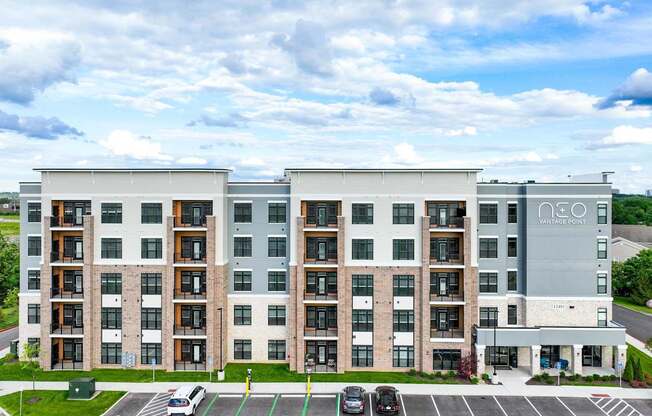 A large apartment building with a parking lot in front.