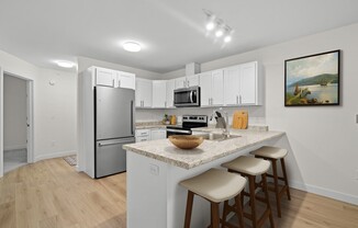 a kitchen with a marble counter top and a stainless steel refrigerator