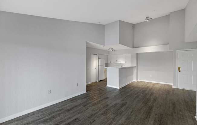 an empty living room and kitchen with white walls and wood floors