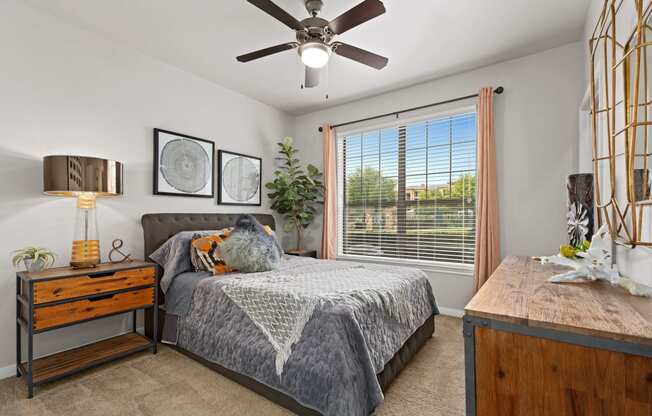 a bedroom with a large window and a ceiling fan