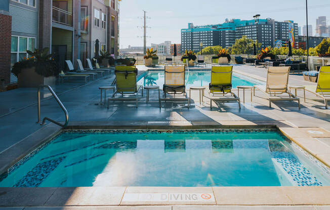the pool on the rooftop of an apartment building with chairs around it