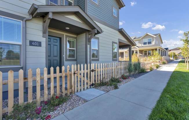 a sidewalk in front of a house with a fence