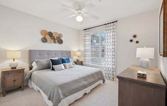 A bedroom with a bed, nightstands, and a ceiling fan.