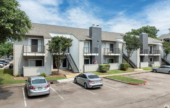 an apartment building with cars parked in a parking lot