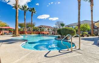 A pool surrounded by palm trees and a clear blue sky.
