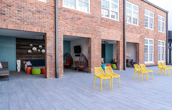 a patio with yellow chairs in front of a brick building