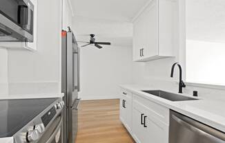 a renovated kitchen with white cabinets and stainless steel appliances