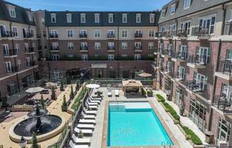 A large pool surrounded by a fence and a building in the background.