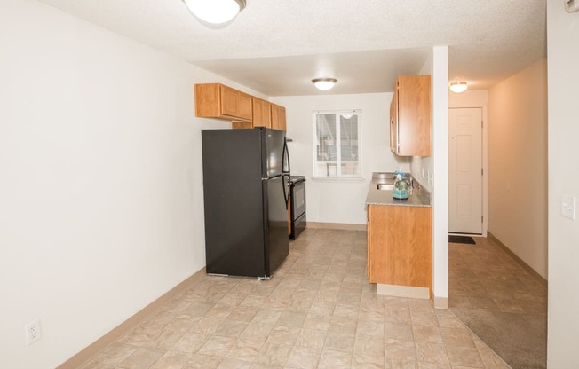 Todd Village vacant apartment dining area and kitchen with black appliances and wood cabinets