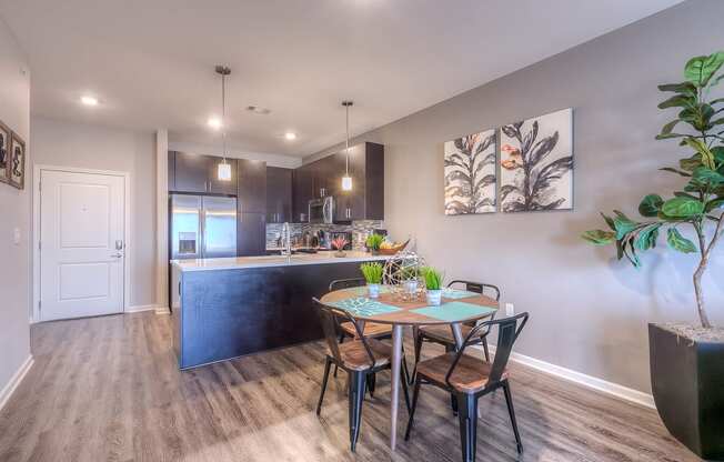 a dining area with a table and chairs and a kitchen in the background