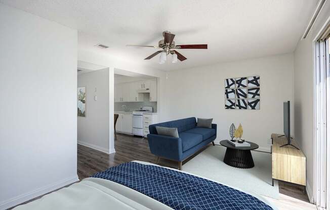 A blue couch sits in a living room with a ceiling fan.