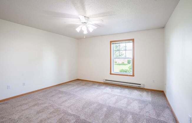 A room with a carpeted floor and a window. Fargo, ND Stonebridge Apartments