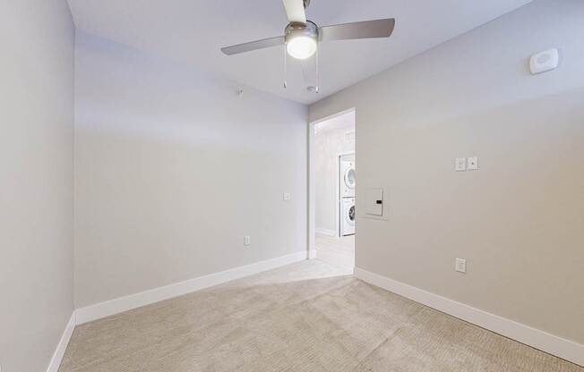 A room with a ceiling fan and carpeted floor.