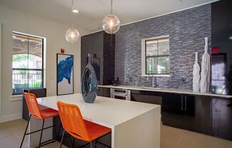 clubhouse kitchen with black cabinets and a white table with orange chairs