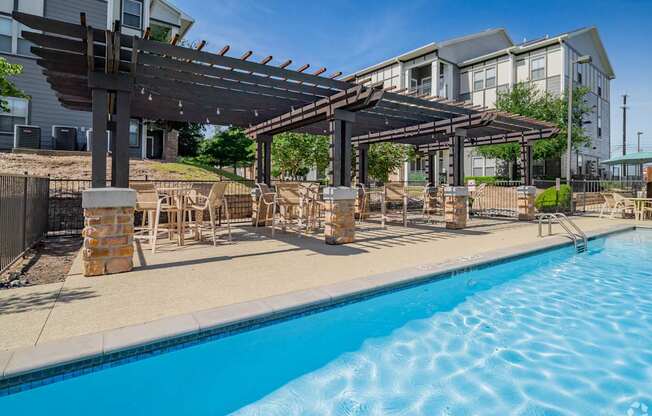 A swimming pool with a wooden pergola over it.